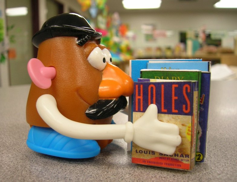 Mr. Potato Head holding books like Holes. 