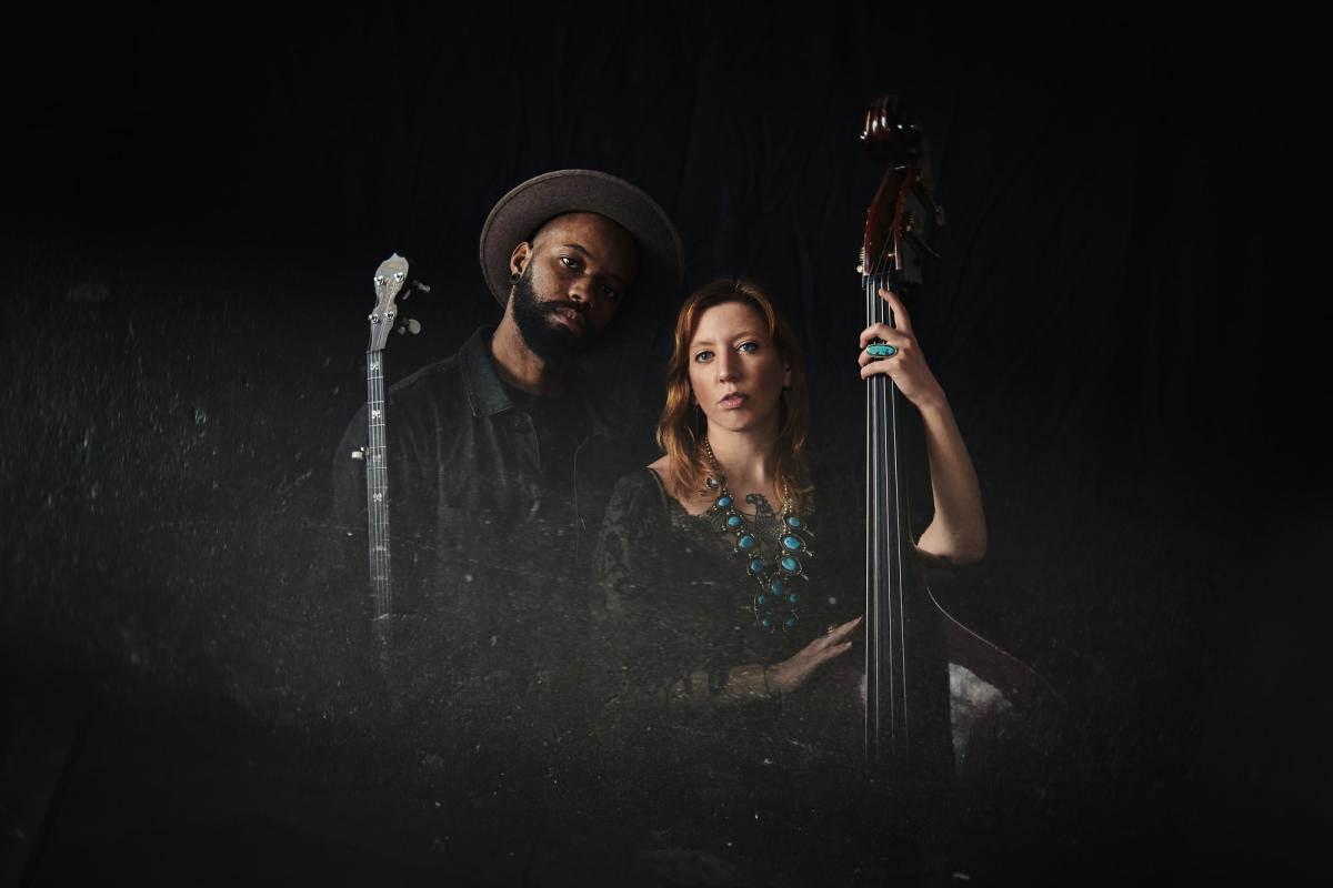 man with banjo and woman with bass. photo by Kat Schleicher