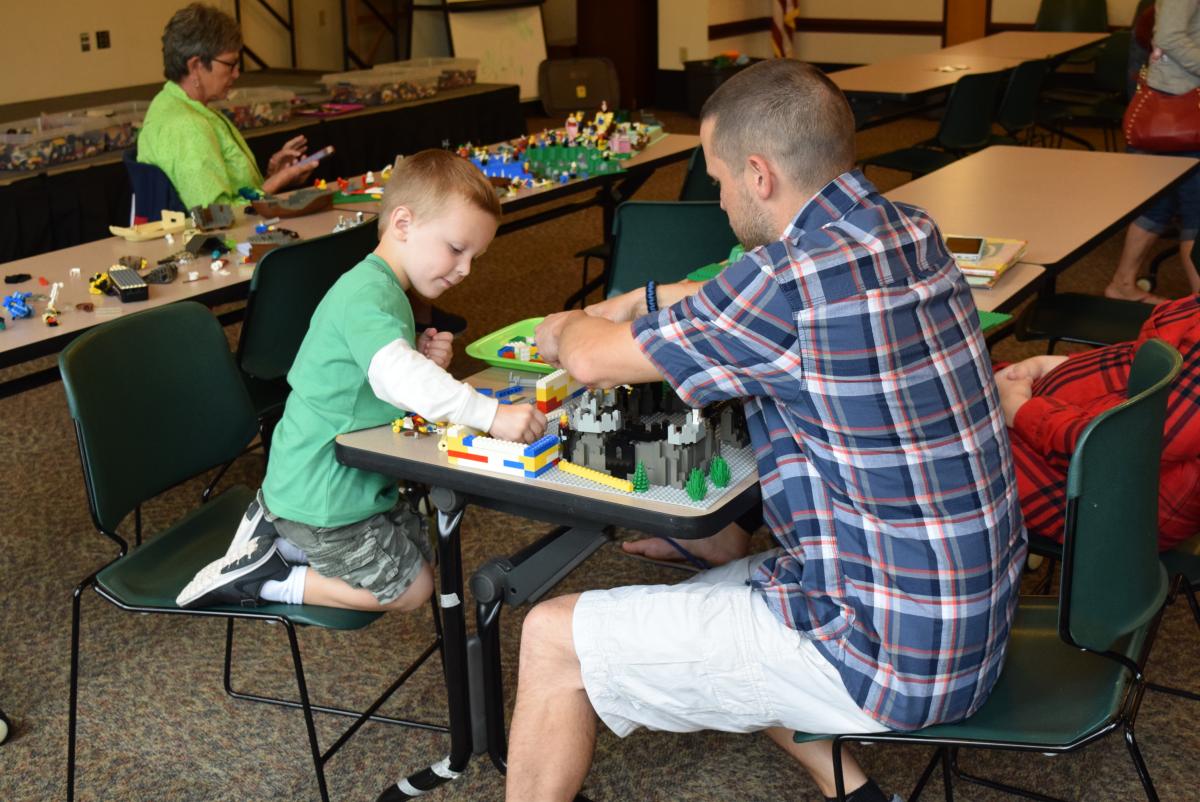 Adult and child playing with LEGOs together.