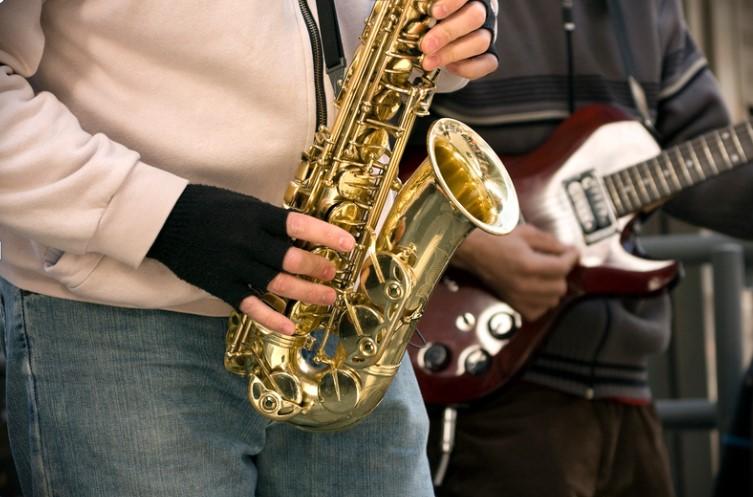 Person playing a saxophone and another playing the guitar